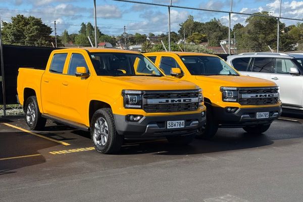 Two yellow JMC double-cab utes parked side by side